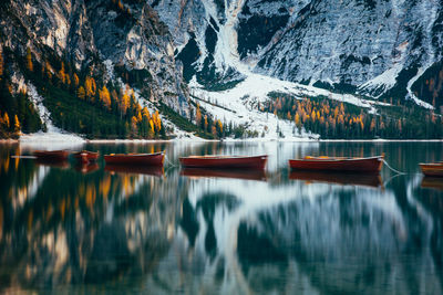 Boats in lake against snowcapped mountains