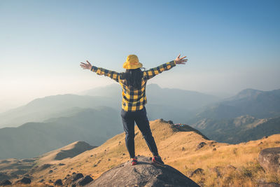 Rear view of man standing on mountain against sky