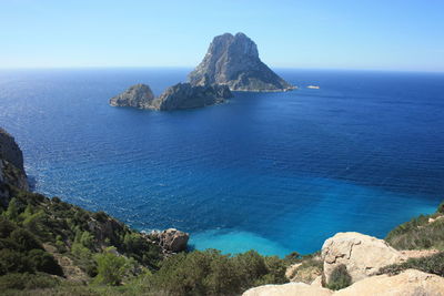 Scenic view of rocks in sea against blue sky