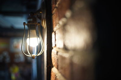 Close-up of illuminated light bulb by wall