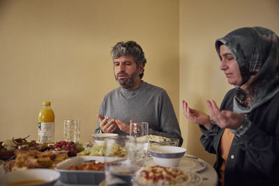 Mature couple praying before eating dinner