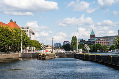 Bridge over river by buildings against sky