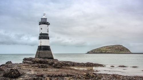 Lighthouse on beach against sky