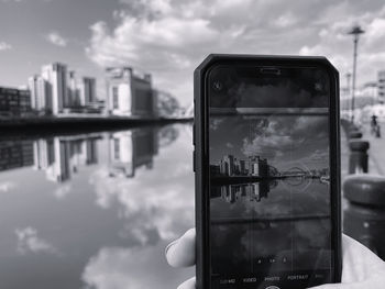 Reflection of man photographing in city