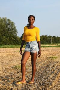 Full length portrait of woman standing on grass against sky