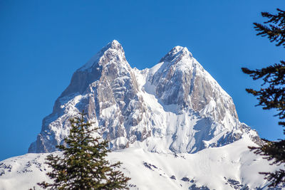 Scenic view of snow covered mountains against clear blue sky