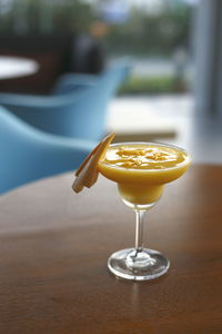 Close-up of refreshing mango smoothie served on a cocktail glass at a bar