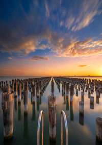 Panoramic view of wooden posts in sea against sky