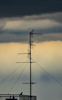 Low angle view of electricity pylon against sky during sunset