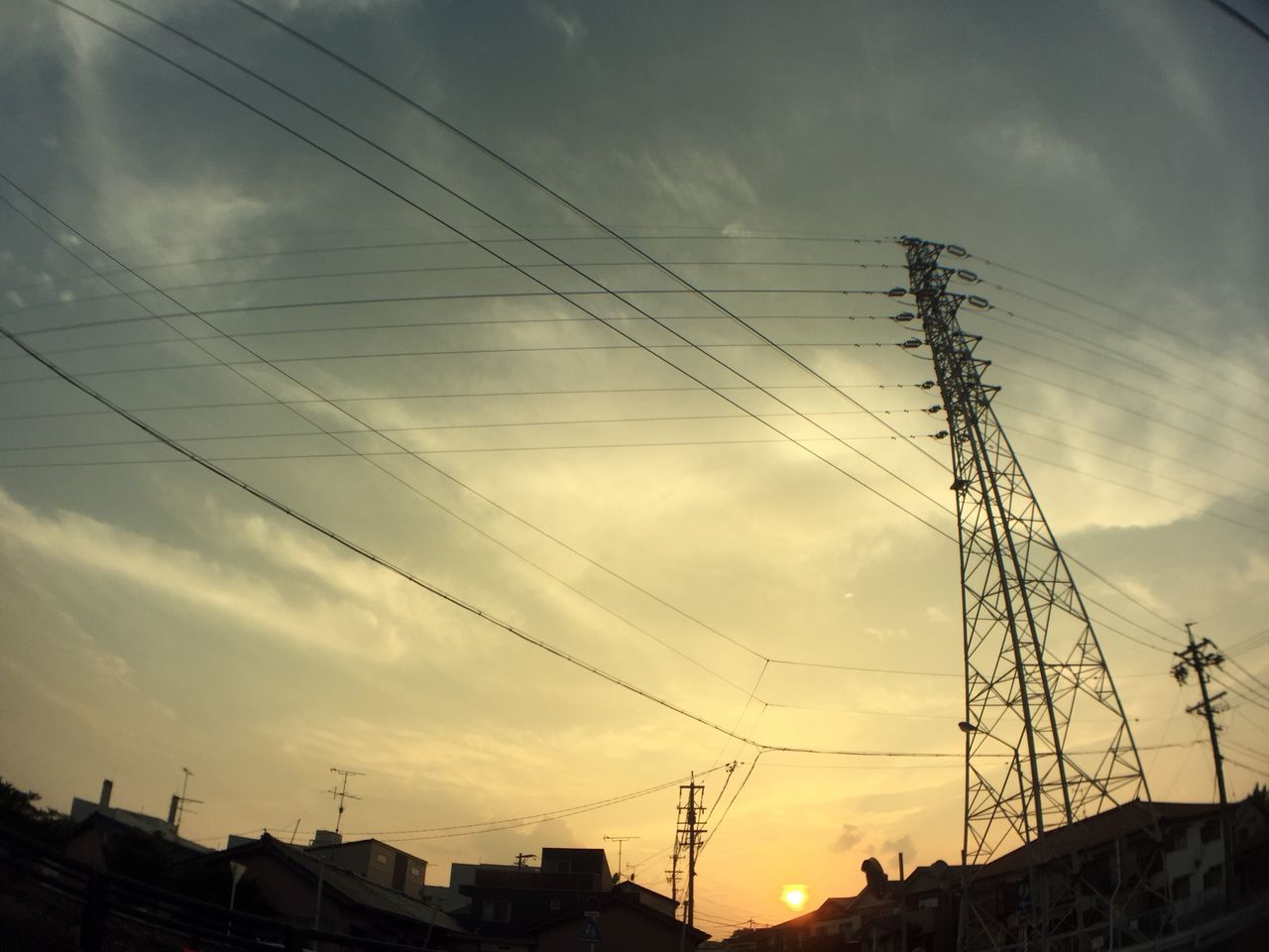 power line, building exterior, electricity pylon, sky, architecture, built structure, sunset, cable, electricity, low angle view, power supply, silhouette, cloud - sky, connection, cloud, residential structure, house, city, power cable, residential building