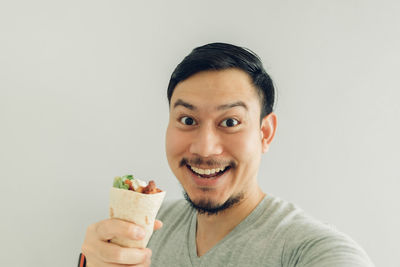 Portrait of man holding food against white background