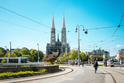 Cable car on street by votive church against clear sky