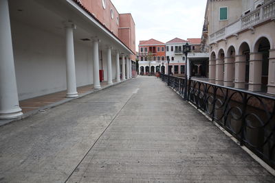 Empty footpath amidst buildings in city