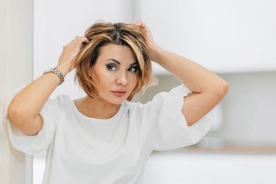 A beautiful woman in a white t-shirt preens for a date, straightens her hair, hair. mock-up. closeup