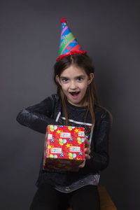 Portrait of girl holding multi colored face against gray background