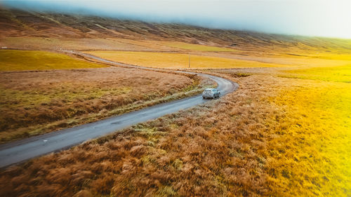 Scenic view of road amidst field against sky