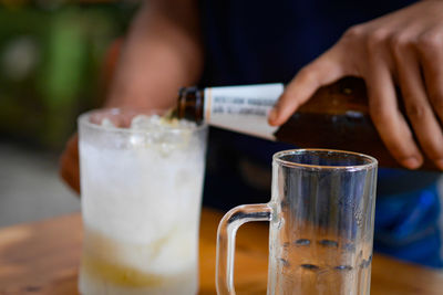 Close-up of hand holding drink on table