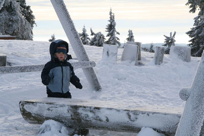 Boy playing on snow covered field at park