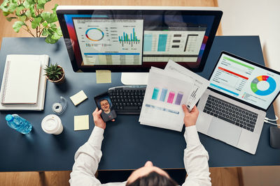 Businessman having video call on smartphone. analyst working with data on charts on computer screen