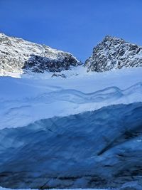 Scenic view of snowcapped mountains against blue sky