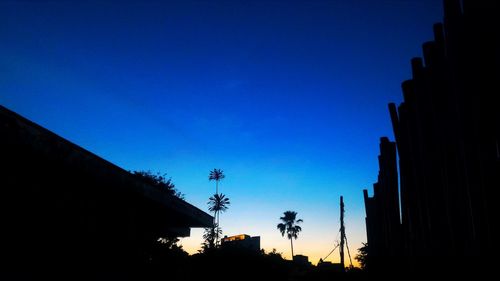 Low angle view of silhouette trees against clear blue sky