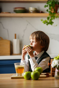 Cute schoolboy makes fresh apple juice for breakfast. vitamins and healthy nutrition for schoolers