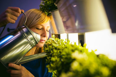 Woman watering potted plants at greenhouse