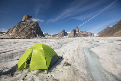 Green tent on glacier in mountian landscape, baffin island