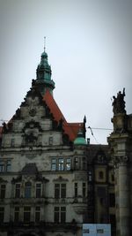 Statue in city against sky