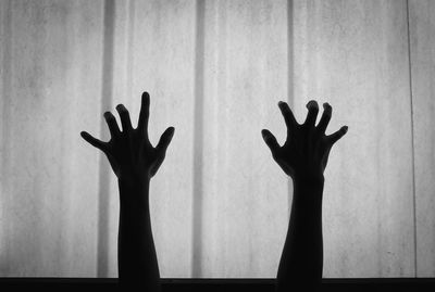 Silhouette of hands gesturing against wall at home