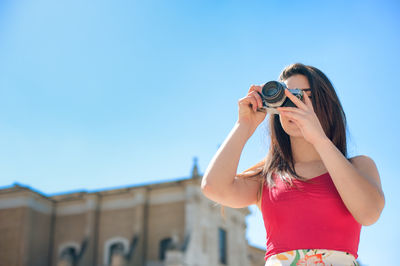 Female photographer against clear blue sky