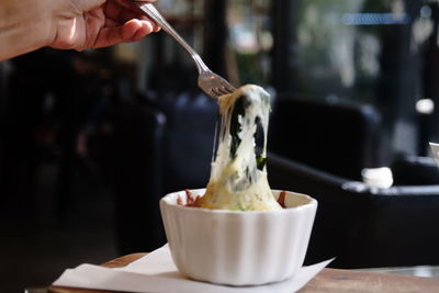 Midsection of person holding ice cream on table