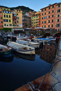 Boats moored at harbor against buildings in city