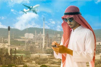Low angle view of man using mobile phone against cityscape