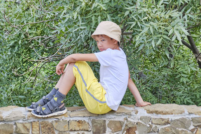 Side view of boy sitting on plants