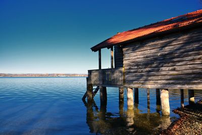 Scenic view of lake by building against clear blue sky