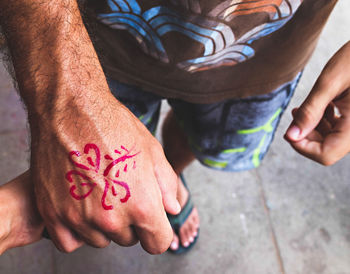 High angle view of man with flower painted on his hand