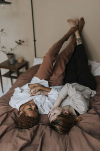 Non-binary couple spending leisure time relaxing on bed at home