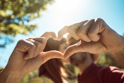 Close-up of hands against sky