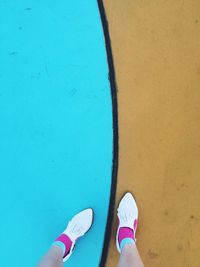 Low section of woman standing on blue and brown floor at skateboard park