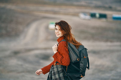 Young woman smiling while standing against blurred background