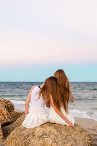 Rear view of woman standing at beach against sky