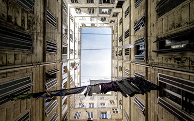 Directly below shot of clothes hanging amidst buildings against sky