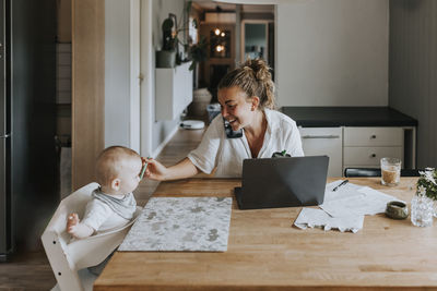 Multitasking mother taking care of baby and working from home