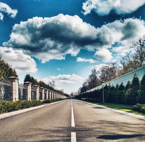 Road by trees against blue sky