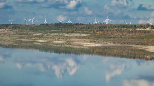 Panoramic view of wind turbines on land against sky