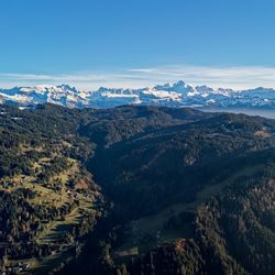 High angle view of trees and mountains against blue sky