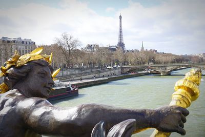 Statue of bridge over river against cloudy sky in paris 