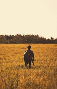 Rear view of man standing on field against clear sky