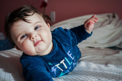 Portrait of cute baby girl on bed at home